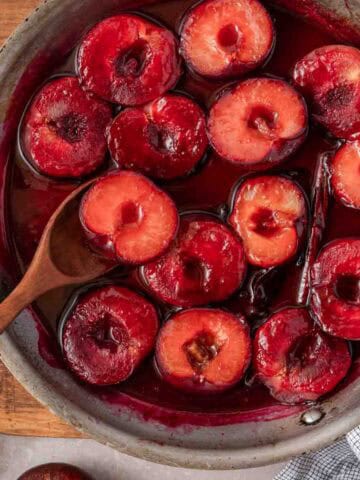 cooked plum halves in liquid in skillet.