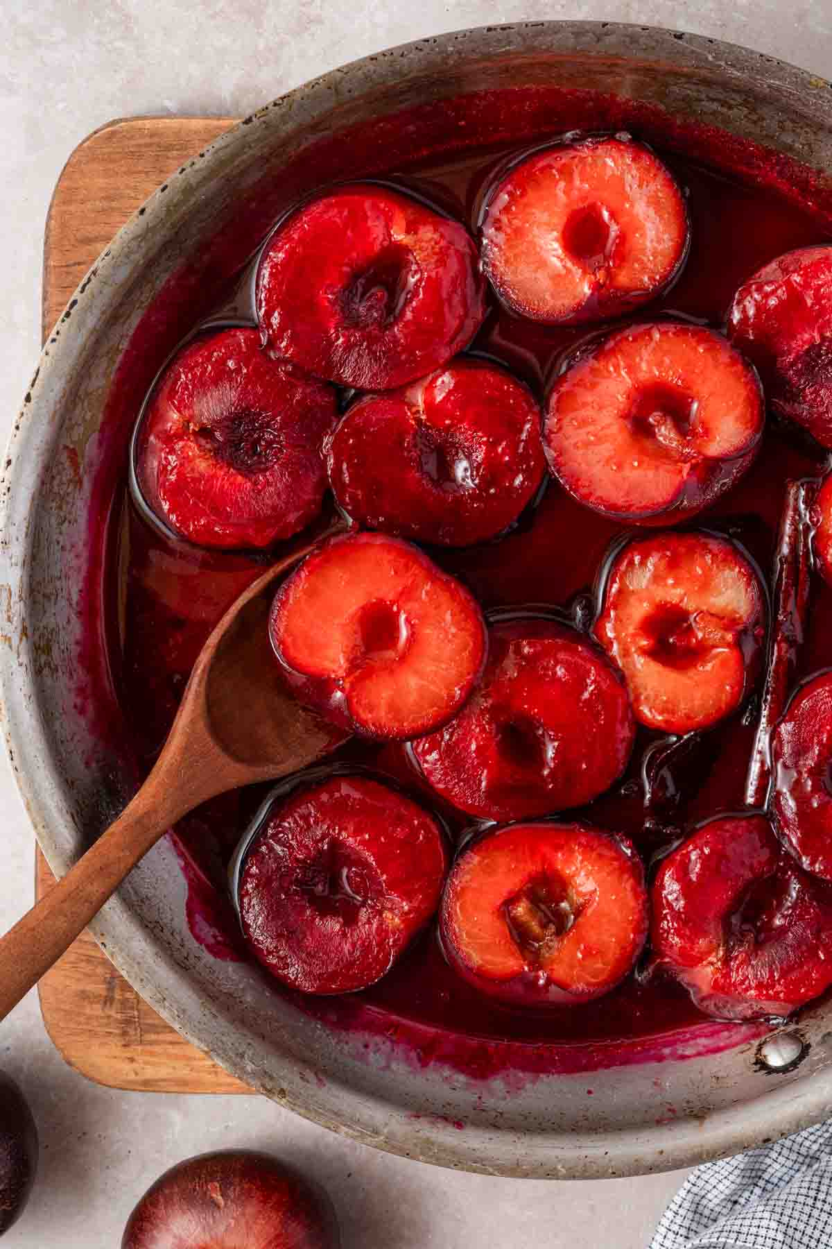 pan of stewed plums with wooden spoon.