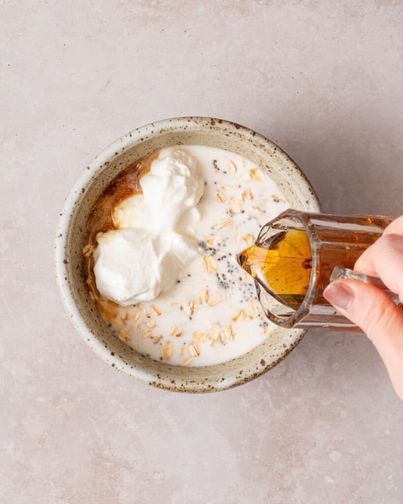 syrup being poured into bowl of dry ingredients for overnight oats.