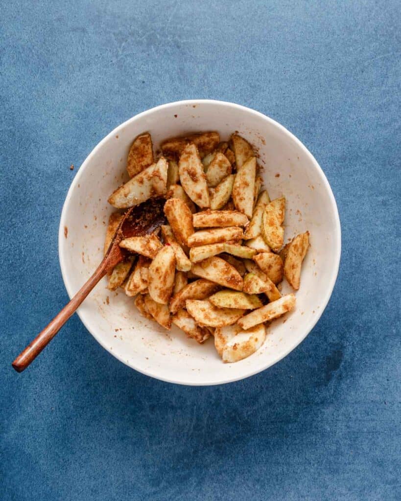 apple galette filling in bowl with wooden spoon.