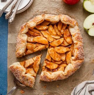apple galette with slice cut out and apples on the side.