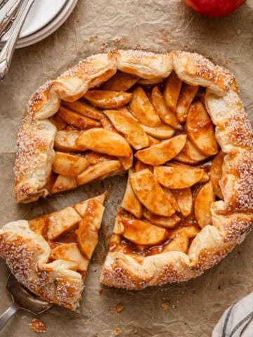 apple galette with slice cut out and apples on the side.