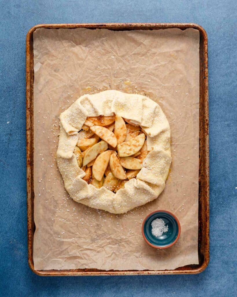 puff pastry before cooking on a baking tray with crust covered in egg wash and coarse sugar with dish of coarse sugar on the side.