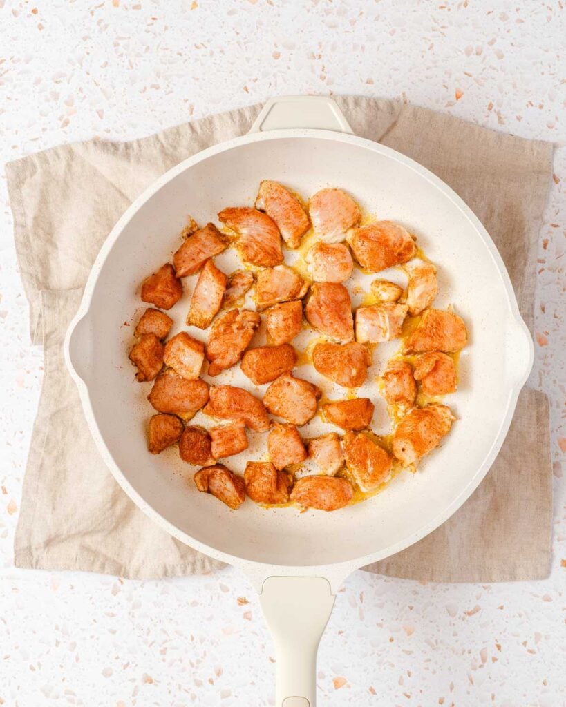 chunks of seasoned chicken in pan.