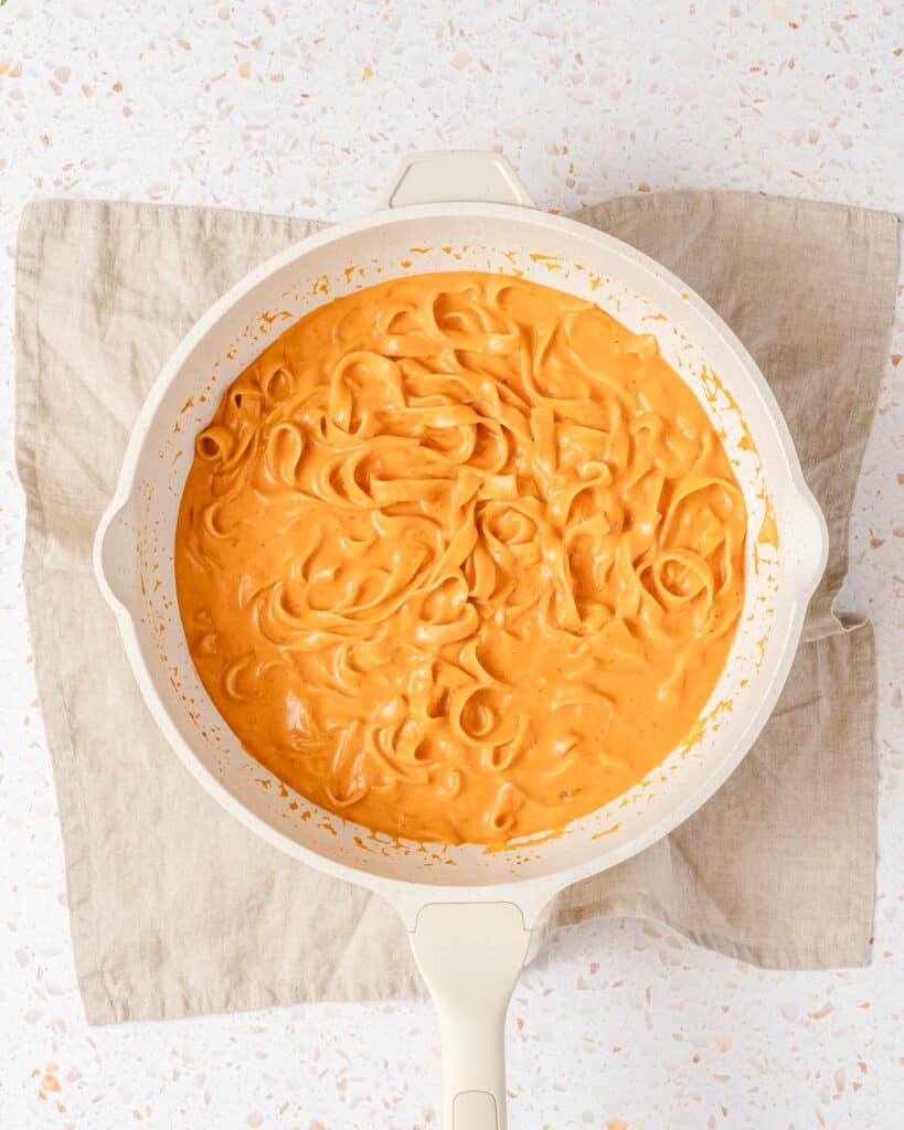 cooked pasta in creamy sauce in pan.