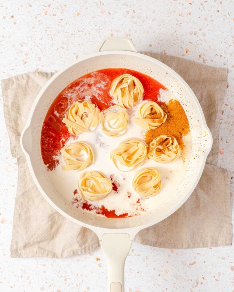 pasta cream seasoning and crushed tomatoes in pan.