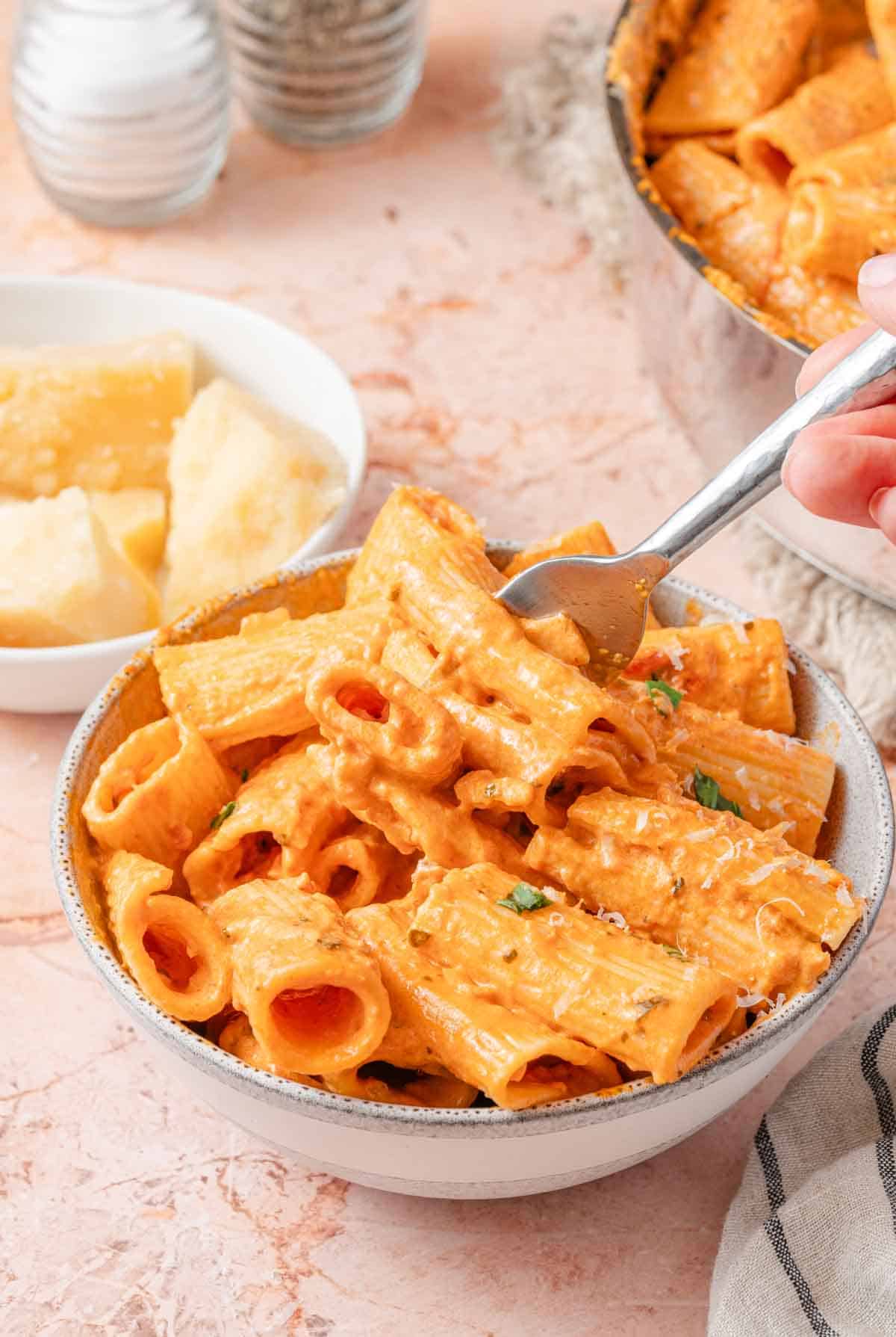 bowl of pink sauce pasta with fork taking a bite.