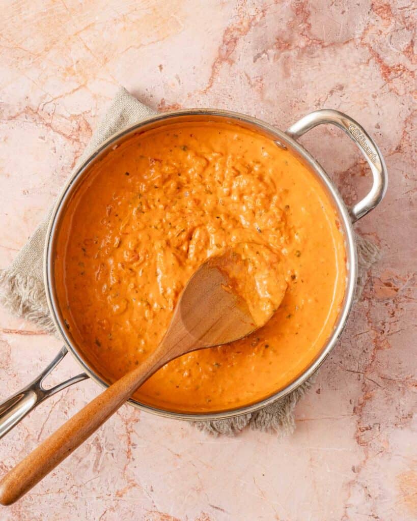 creamy tomato sauce in pan with wooden spoon.