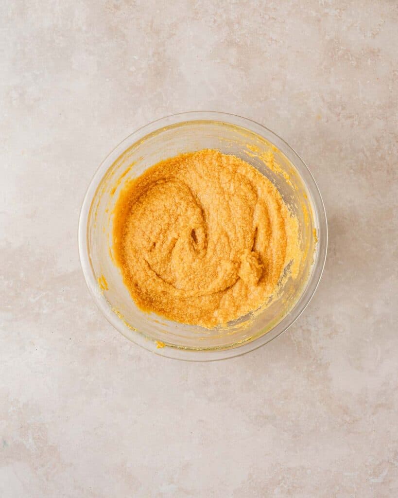 butter sugar pumpkin and egg mixed in bowl.