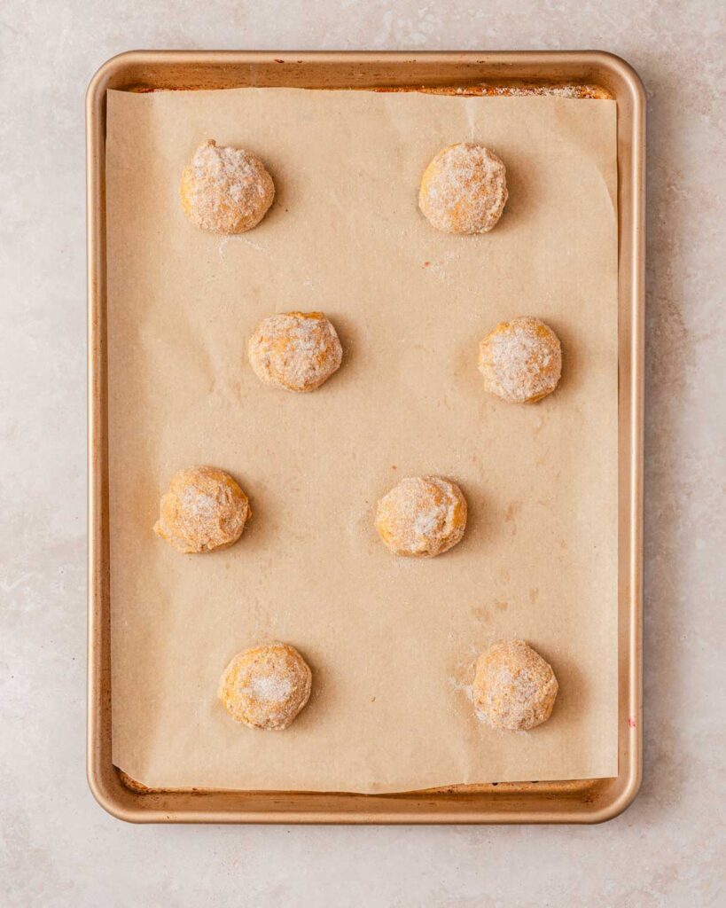 cookie dough balls on parchment lined baking sheet.