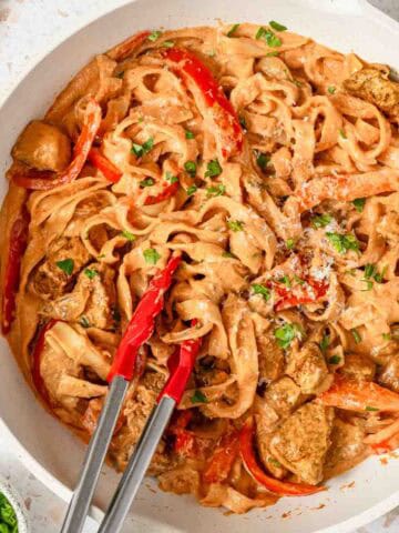 pot of creamy pasta with cajun seasoning and chunks of chicken.