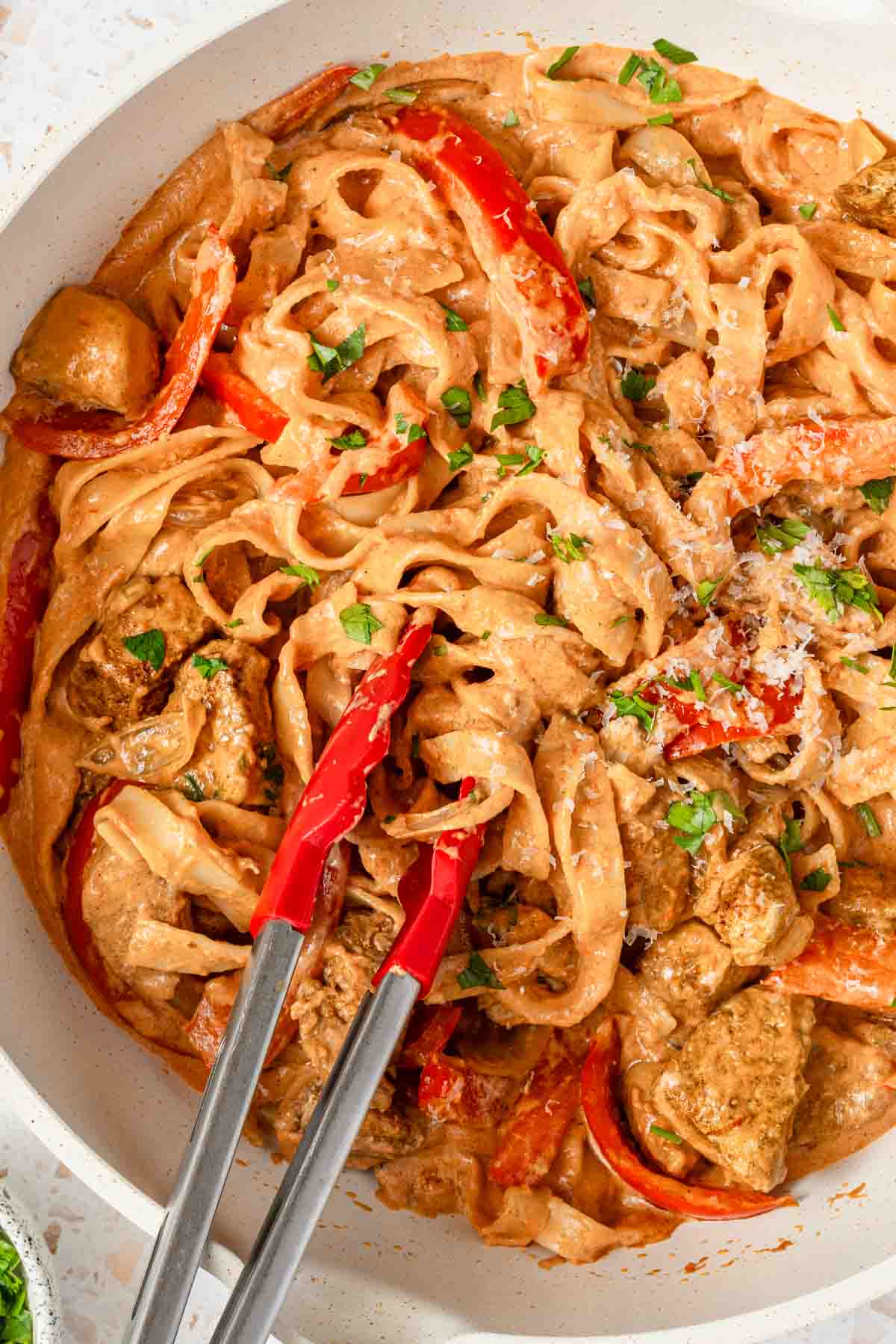 pot of creamy chicken pasta with tongs in pot.