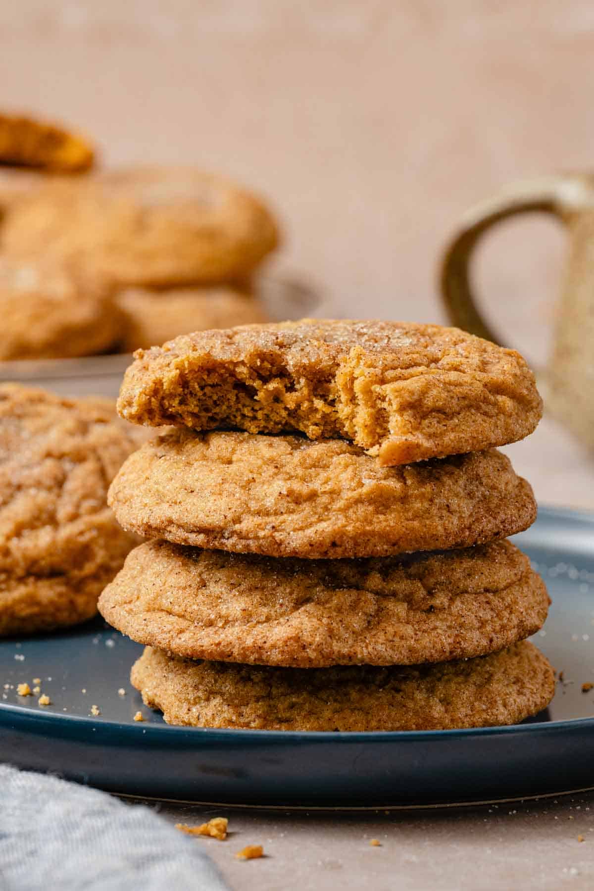 stack of pumpkin cookies on plate with bite taken out of one.